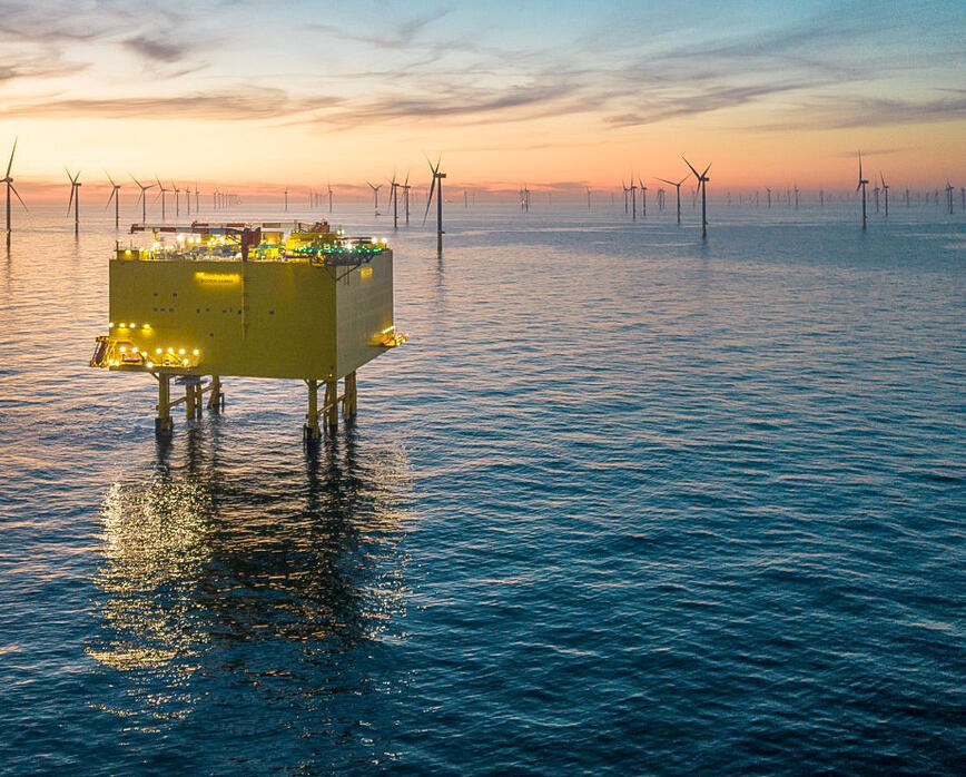 Offshore-Plattform bei Dämmerung mit Windkraftanlagen im Hintergrund